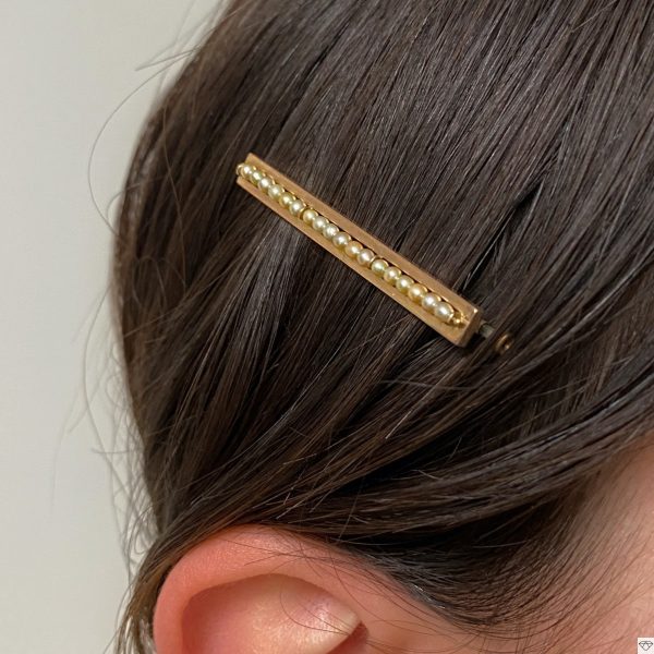 Barrette vintage en or jaune rectangulaire ornée d'une ligne de perles portée dans les cheveux