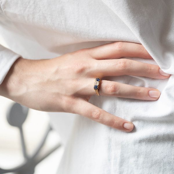 Bague Jarretière sertie de diamant et saphir en porté sur chemise blanche